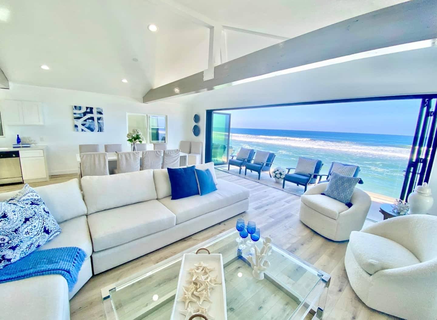 Living room seating with the ocean framed by the open glass wall